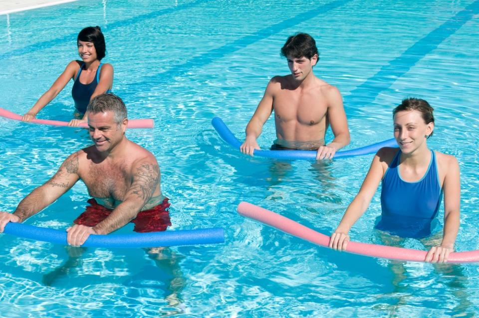 Adults doing water aerobics with noodles