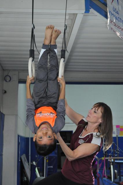 Boy hangs upside down on the gymnastics rings