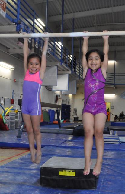 Girls hanging on the uneven bars