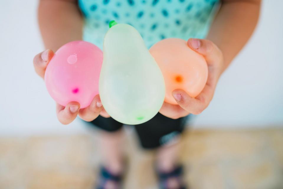 Child's hand holding water balloons