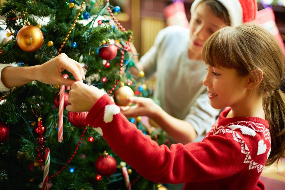 Children hanging ornaments on Christmas Tree