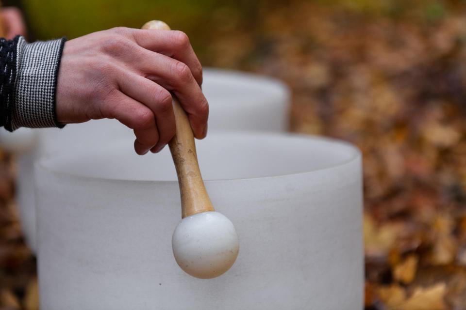 Hands using a wand-type device on a sound bowl
