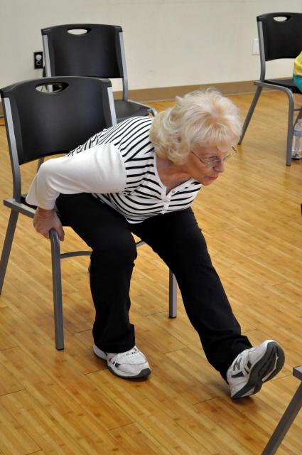 Senior woman stretching forward in a chair