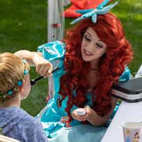 Woman dressed as Ariel from Little Mermaid face painting child